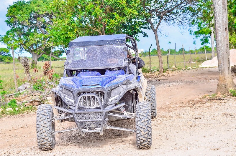 Buggy azul parado en un camino de tierra del campo dominicano