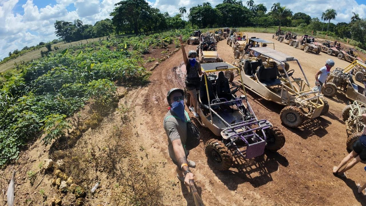 Fila de buggies en un camino de tierra, con un viajero saludando a la cámara
