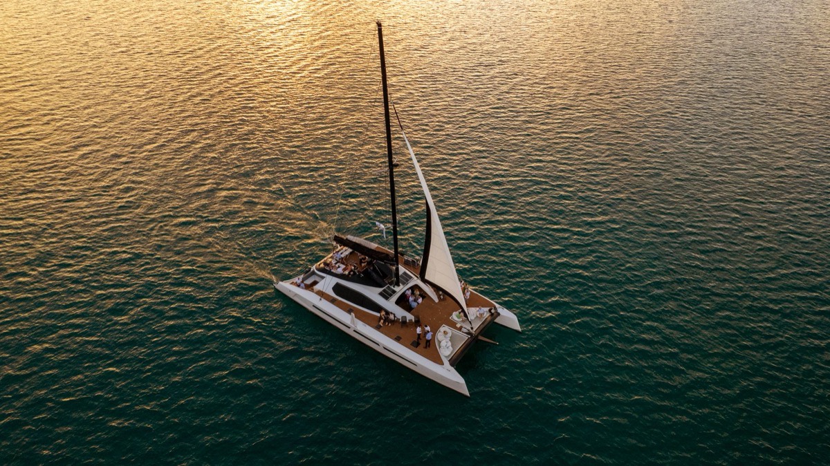 Catamarán navegando al atardecer, visto desde el aire