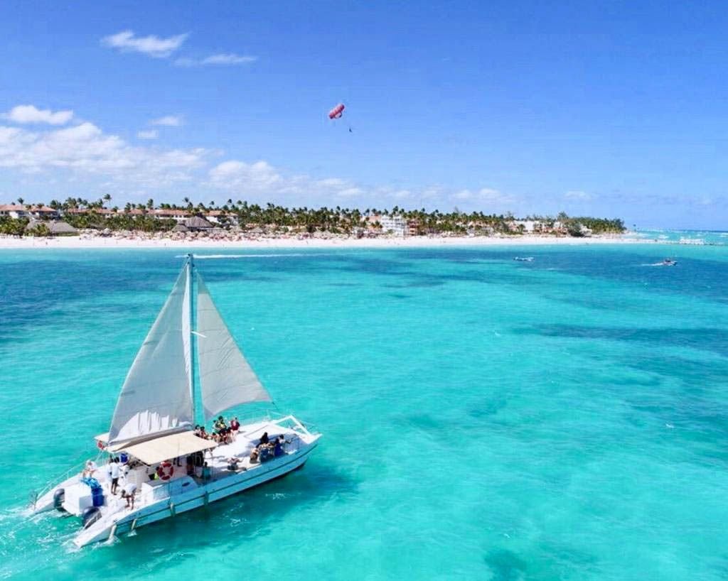 Catamarán a vela sobre agua turquesa frente a la costa de Bávaro