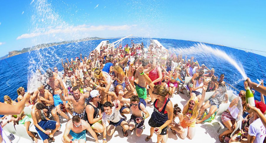 La cubierta del barco llena de gente celebrando, con el mar detrás