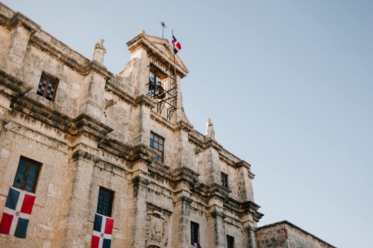 Fachada de piedra de un edificio colonial con banderas dominicanas