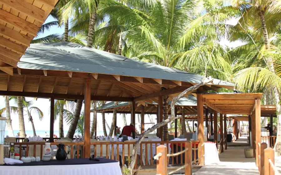 A wooden beach pavilion set for lunch, among the palms