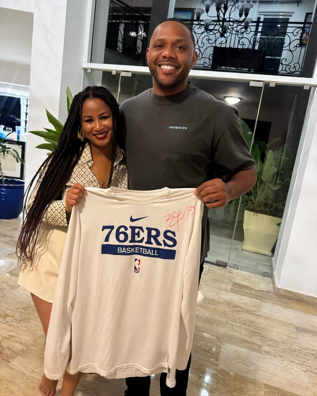 Rayma and Eric Gordon holding up a 76ers shirt signed by him.