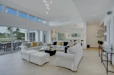 Salón de doble altura con sofás blancos