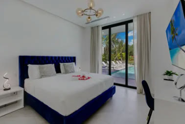A bedroom with a blue headboard opening onto the pool