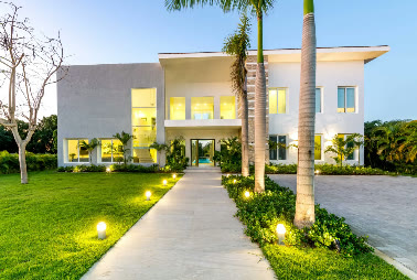 La villa iluminada de noche desde el camino de entrada