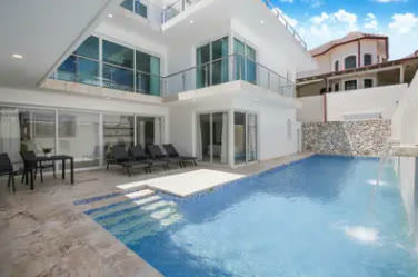 Piscina de la villa con la fachada blanca de tres niveles