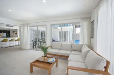 Salón blanco con sofás y salida a la terraza