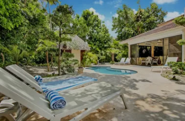 Piscina con tumbonas y el rancho de palma