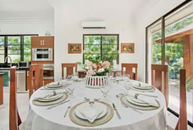 Comedor con mesa redonda vestida y la cocina al fondo