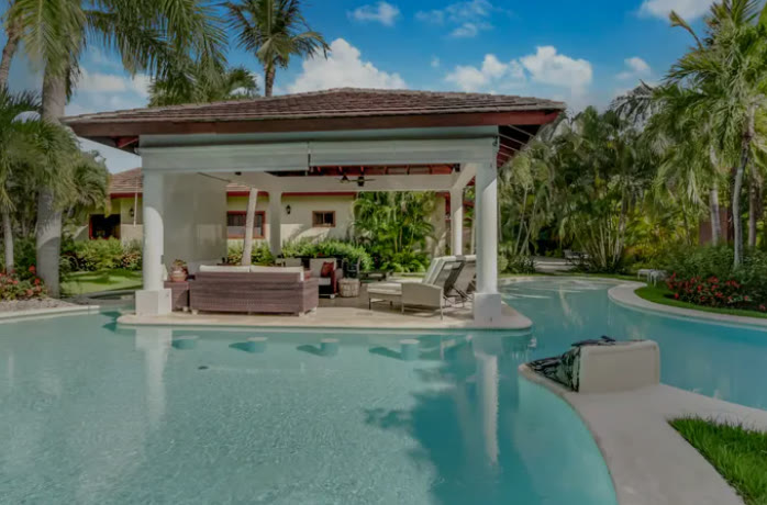 The pool with its roofed gazebo and palm trees