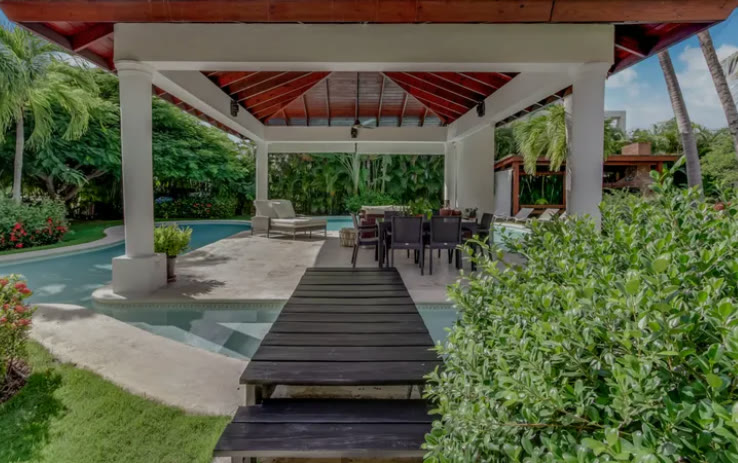 A pergola with a wooden walkway over the pool